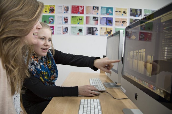 Das Foto zeigt zwei junge Frauen, die auf einen Monitor schauen und sich beraten