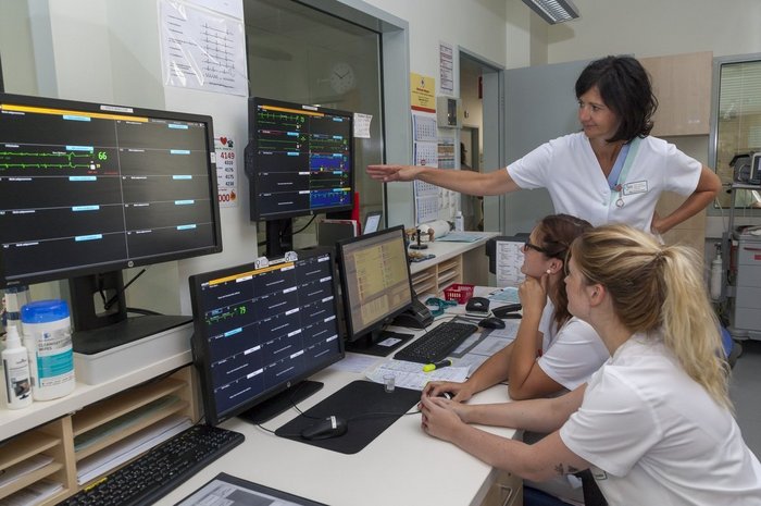 Das Foto zeigt drei Personen bei der Beobachtung der Überwachungsmonitore einer Intensivstation