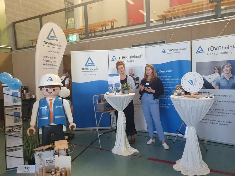 Das Foto zeigt den Messestand des TÜV Rheinland mit zwei Austellerinnen