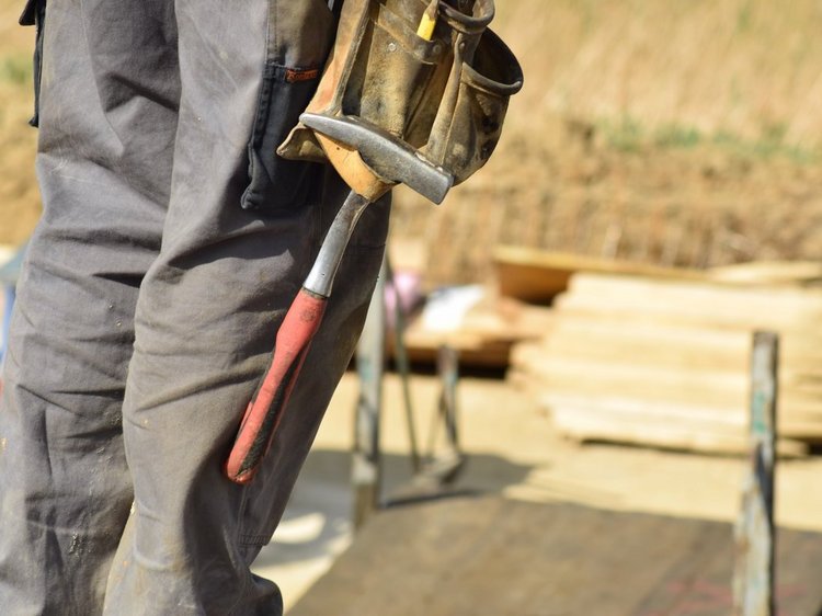 Das Foto zeigt stellvertretend für alle Handwerksberufe Zimmermannshandwerkzeug hängend am Oberschenkel einer Person