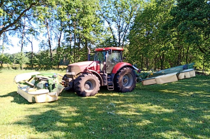 Das Foto zeigt einen Traktor mit zwei Balkenmähwerken