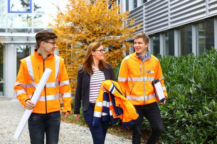 Das Foto zeigt drei junge Menschen vor der Berufsschule